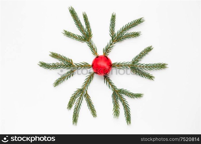 winter holidays, christmas and decorations concept - snowflake shape made of fir branches and red ball on white background. christmas ornament of fir branches and red ball