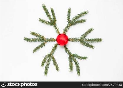 winter holidays, christmas and decorations concept - snowflake shape made of fir branches and red ball on white background. christmas ornament of fir branches and red ball