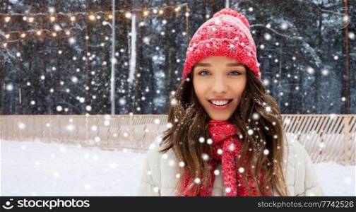 winter holidays, christmas and leisure concept - portrait of happy smiling teenage girl or young woman over skating rink on background. happy teenage girl in winter over skating rink