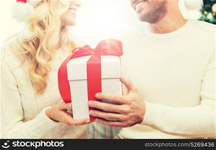 winter, holidays, christmas and people concept - close up of happy couple with christmas gift at home. close up of couple with christmas gift at home