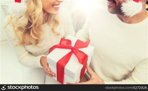 winter, holidays, christmas and people concept - close up of happy couple with christmas gift at home. close up of couple with christmas gift at home