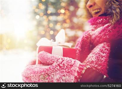 winter holidays, christmas and people concept - close up of happy woman with present or gift box outdoors. close up of woman with christmas gift outdoors