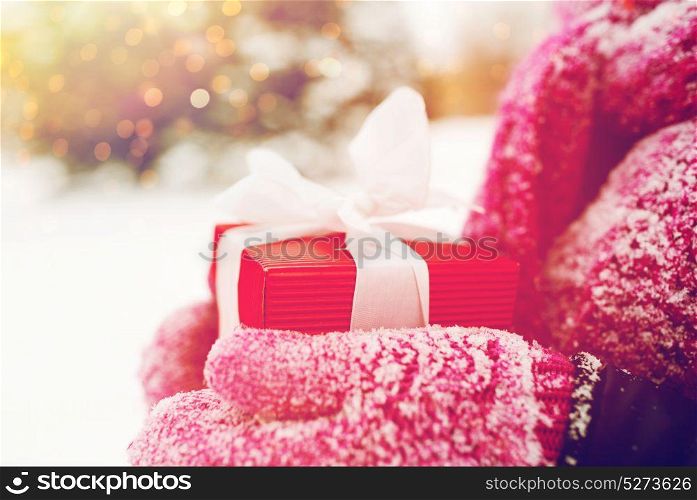 winter holidays, christmas and people concept - close up of woman hands holding present or gift box outdoors. close up of woman holding christmas gift outdoors