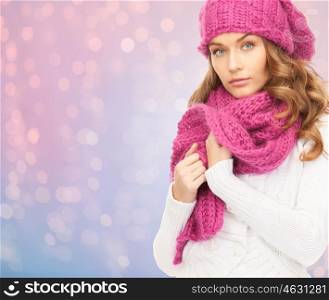 winter holidays, christmas and people concept - close up of young woman in hat and scarf over rose quartz and serenity lights background