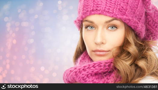 winter holidays, christmas and people concept - close up of young woman in hat and scarf over rose quartz and serenity lights background