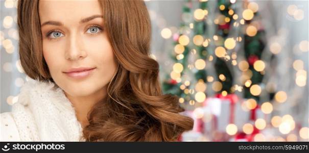 winter holidays, christmas and people concept - happy young woman face over christmas tree lights background