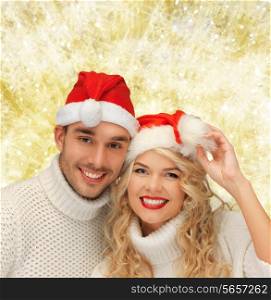 winter, holidays, christmas and people concept - smiling couple in sweaters and santa helper hats over yellow lights background