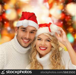 winter, holidays, christmas and people concept - smiling couple in sweaters and santa helper hats over red lights background