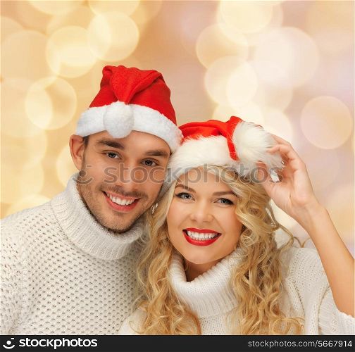 winter, holidays, christmas and people concept - smiling couple in sweaters and santa helper hats over beige lights background