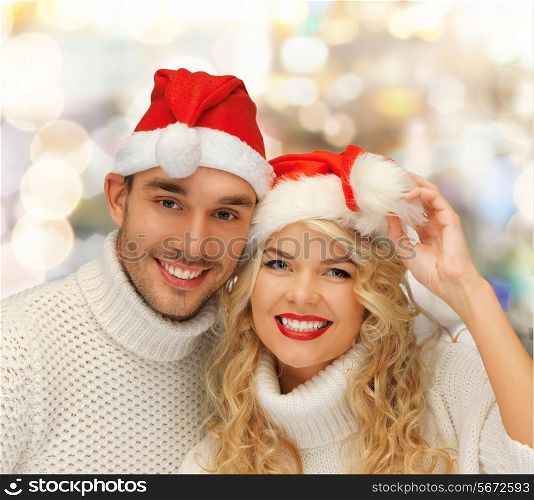 winter, holidays, christmas and people concept - smiling couple in sweaters and santa helper hats over lights background