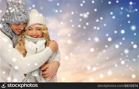 winter, holidays, christmas and people concept - smiling couple in sweaters and hats over snow background. smiling couple in sweaters over snow background