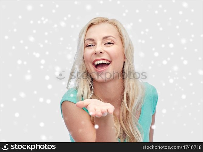 winter holidays, christmas and people concept - smiling young woman or teenage girl holding something on hand over snow