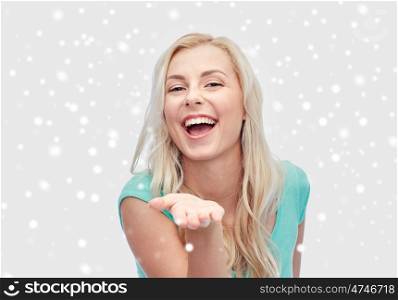 winter holidays, christmas and people concept - smiling young woman or teenage girl holding something on hand over snow
