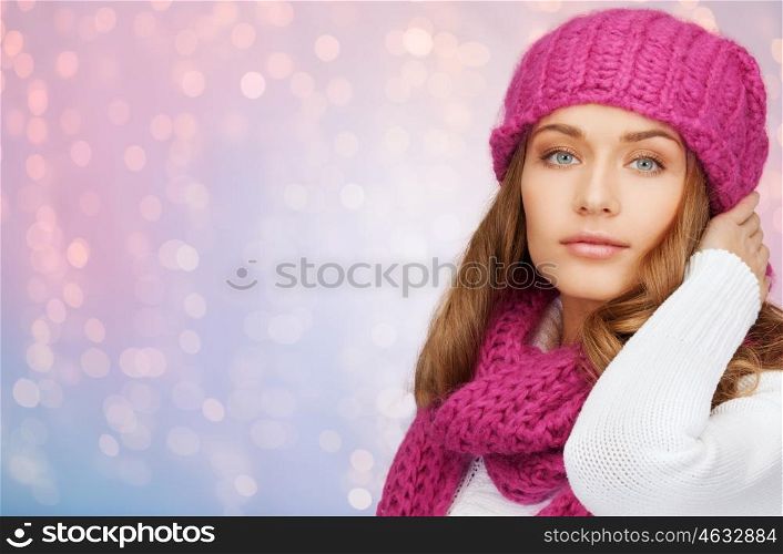 winter holidays, christmas and people concept - young woman in hat and scarf over rose quartz and serenity lights background