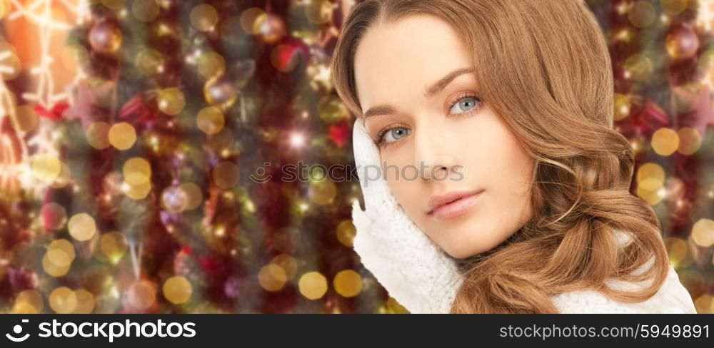 winter holidays, christmas and people concept - young woman in white cloves over lights background