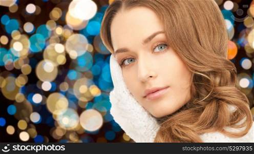 winter holidays, christmas and people concept - young woman in white gloves or mittens over lights background. young woman in gloves over christmas lights
