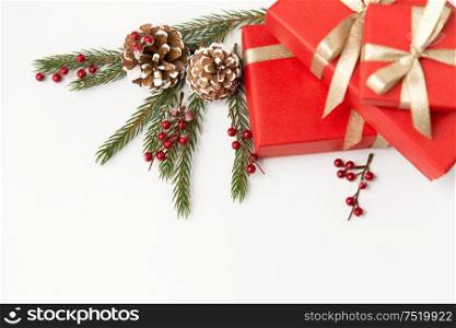 winter holidays, christmas celebration concept - red gift boxes and fir tree branches with pine cones on white background. christmas gifts and fir branches with pine cones