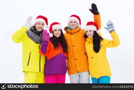 winter holidays, christmas, friendship and people concept - happy friends in santa hats and ski suits outdoors