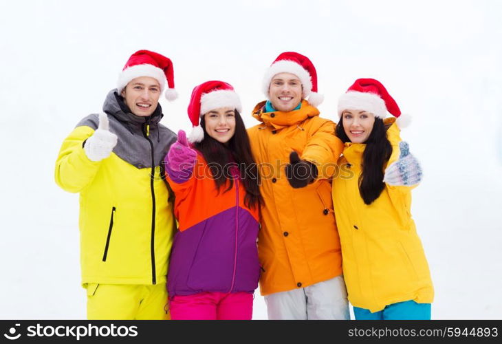 winter holidays, christmas, friendship and people concept - happy friends in santa hats and ski suits outdoors