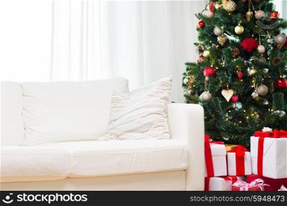 winter holidays, decoration and celebration concept - christmas tree, gift boxes and sofa at home room