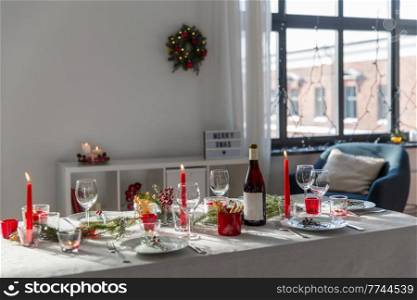winter holidays, dinner party and celebration concept - christmas table serving with candles, crockery and wine at home. christmas dinner party table serving at home