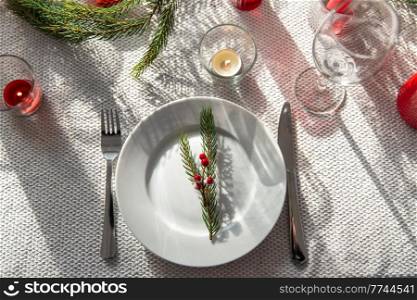winter holidays, dinner party and celebration concept - christmas table serving with candles, plates and cutlery at home. christmas dinner party table serving at home