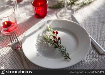 winter holidays, dinner party and table serving concept - close up of plate with christmas decoration, knife and fork at home. christmas dinner party table serving at home