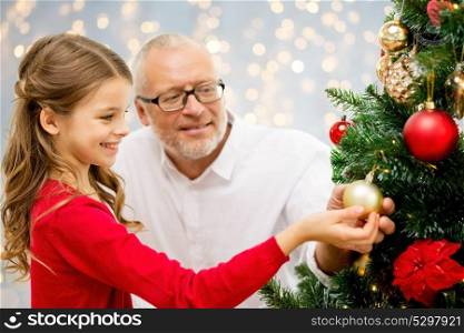 winter holidays, family and people concept - happy grandfather and granddaughter decorating christmas tree happy over lights background. grandfather and granddaughter at christmas tree