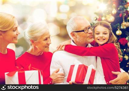 winter holidays, family and people concept - happy grandparents and granddaughter with christmas gifts over lights background. happy family with christmas gifts over lights