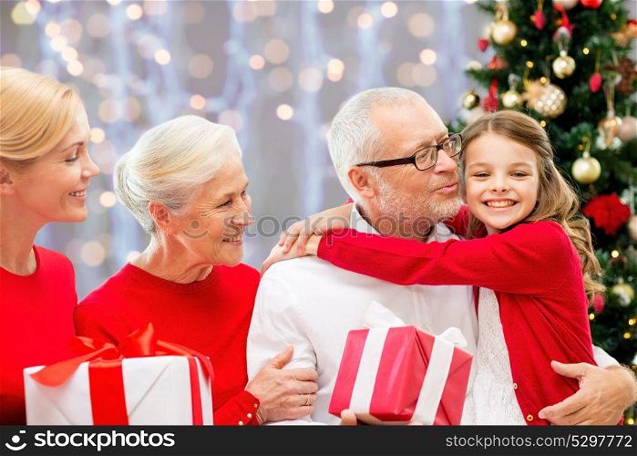 winter holidays, family and people concept - happy grandparents and granddaughter with christmas gifts over lights background. happy family with christmas gifts over lights
