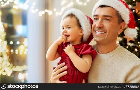 winter holidays, family and people concept - happy middle-aged father and baby daughter over christmas lights at home. happy father and baby girl over christmas lights