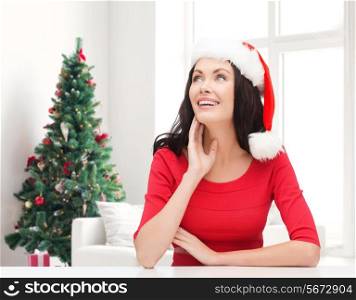 winter, holidays, happiness and people concept - smiling woman in santa helper hat over living room with christmas tree background