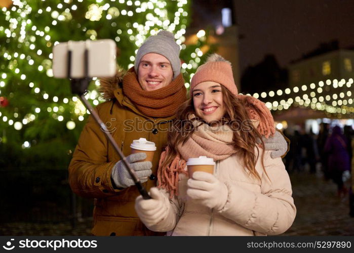 winter holidays, hot drinks and people concept - happy couple with coffee taking selfie in christmas evening. couple with coffee taking selfie at christmas