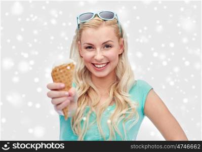 winter holidays, junk food and people concept - young woman or teenage girl with sunglasses eating ice cream over snow