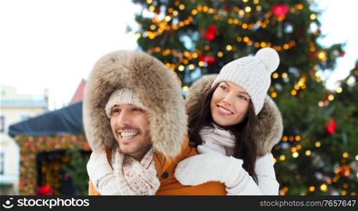 winter holidays, leisure and people concept - happy couple having fun over christmas market background. happy couple over christmas market background