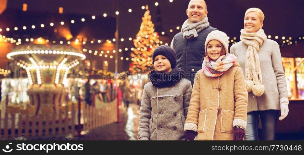 winter holidays, leisure and people concept - happy family over evening christmas market or amusement park background. happy family at christmas market or amusement park