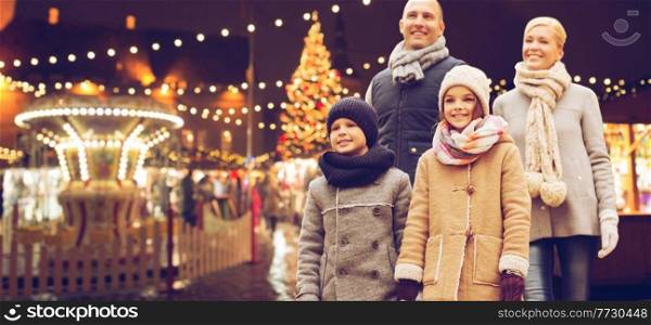 winter holidays, leisure and people concept - happy family over evening christmas market or amusement park background. happy family at christmas market or amusement park