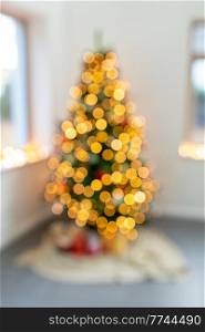 winter holidays, new year and celebration concept - blurred christmas tree lights at home. blurred christmas tree lights at home