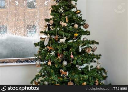winter holidays, new year and celebration concept - green artificial christmas tree decorated with vintage toys at home. decorated artificial christmas tree at home
