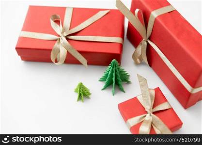 winter holidays, new year and celebration concept - red gift boxes and origami christmas trees on white background. gift boxes and christmas trees on white background