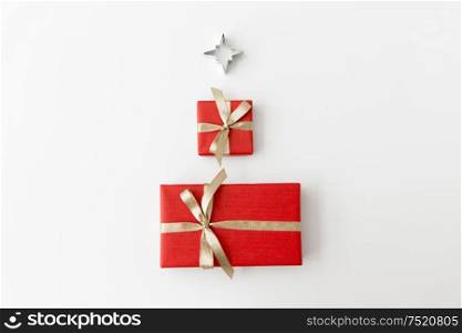winter holidays, new year and celebration concept - red gift boxes and kitchen mold in shape of star on white background. red christmas gifts and mold in shape of star