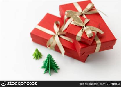 winter holidays, new year and celebration concept - red gift boxes and origami christmas trees on white background. gift boxes and christmas trees on white background