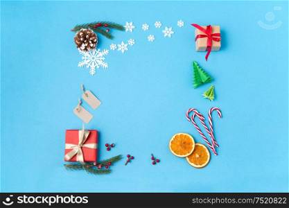 winter holidays, new year and christmas concept - frame made of gift boxes, fir tree branches, tags and decorations on blue background. frame of gifts, fir branches, tags and decorations