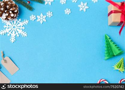 winter holidays, new year and christmas concept - gift box, fir tree branches, tags and decorations on blue background. christmas gift, tags and decorations