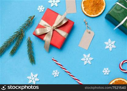 winter holidays, new year and christmas concept - gift boxes, fir tree branches, tags and decorations on blue background. christmas gifts, branches, tags and decorations