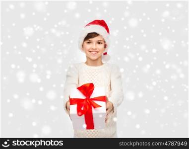 winter holidays, presents, christmas, childhood and people concept - smiling happy boy in santa hat with gift box over snow background
