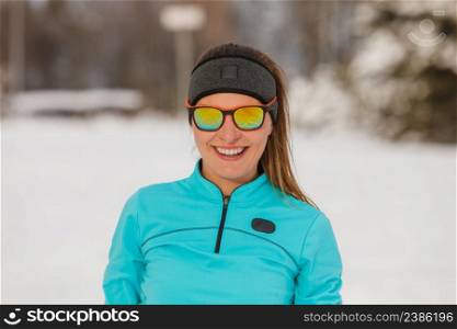 Winter holidays, sporty people concept. Lady spending free time in park. Sporty girl wearing sunglasses enjoying good wintry weather.. Lady spending free time in park.