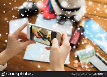 winter holidays, tourism, travel, technology and people concept - woman with smartphone photographing map and beach stuff