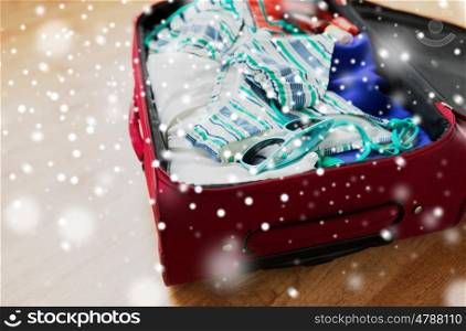 winter holidays, vacation, tourism and objects concept - close up of travel bag with beach clothes and sunglasses over snow