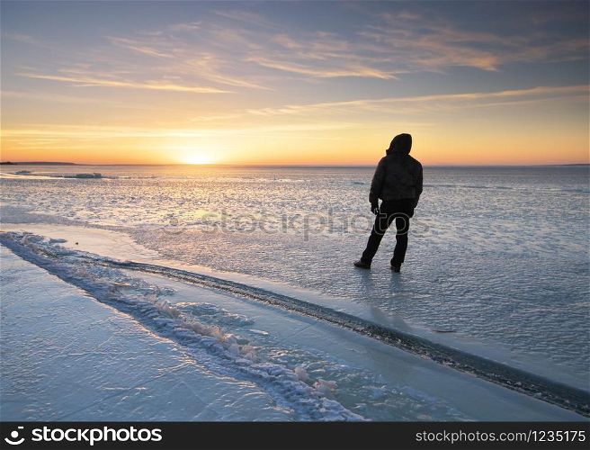 Winter landscape and man looking on sunset. Ice blocks. Composition of nature.